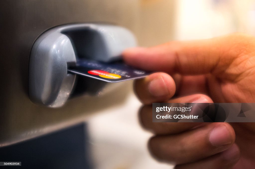 Man inserting a bank Credit Card in a pay phone