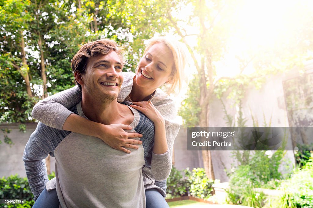 Man giving piggyback ride to woman in backyard