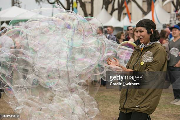 young woman playing with bubbles at treasure island music festival - treasure island music festival 2015 stockfoto's en -beelden