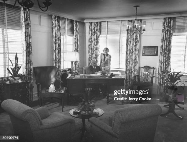 Motion picture executive Samuel Goldwyn sitting in his office with his secretary.