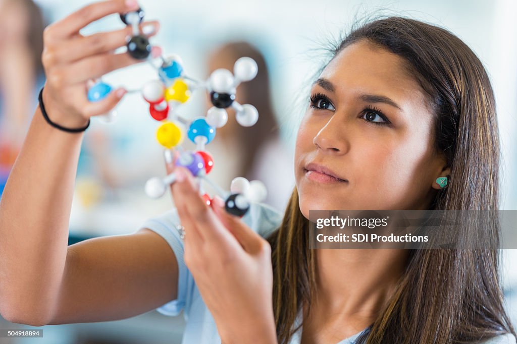 High school girl studying model molecule in science class
