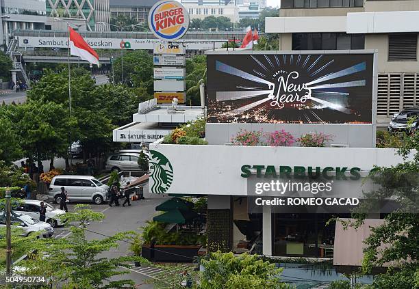 Indonesian police secure the area outside a damaged Starbucks coffee shop after a series of explosions hit central Jakarta on January 14, 2016....