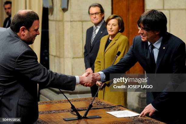 Ewly elected president of the Catalonian regional government Carles Puigdemont shakes hands with government vice-president and chief of Economy and...