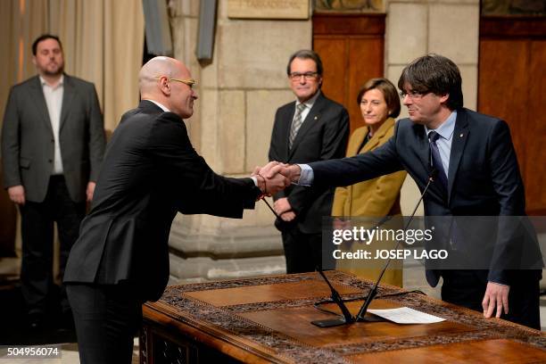 Newly elected president of the Catalonian regional government Carles Puigdemont shakes hands with chief of foreign affairs, institutional relations...