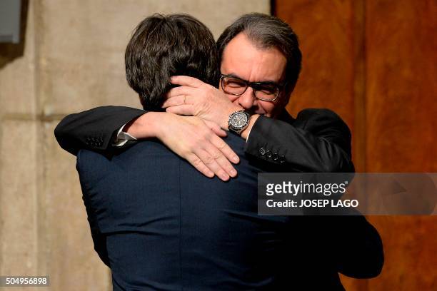 Outgoing Catalan regional president Artur Mas hugs his successor Carles Puigdemont during the new cabinet members swearing-in ceremony at the...