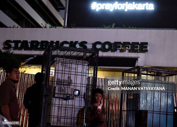 Young Indonesian boy sips a drink outside the damaged Starbucks coffee shop after a series of explosions hit central Jakarta on January 14, 2016. A...