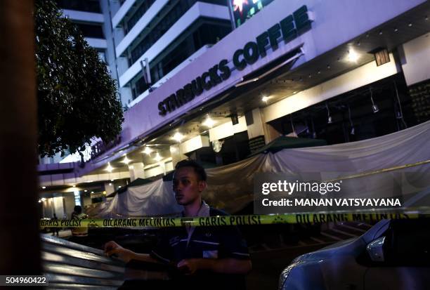 An Indonesian man puts up metal-sheets outside the damaged Starbucks coffee shop after a series of explosions hit central Jakarta on January 14,...