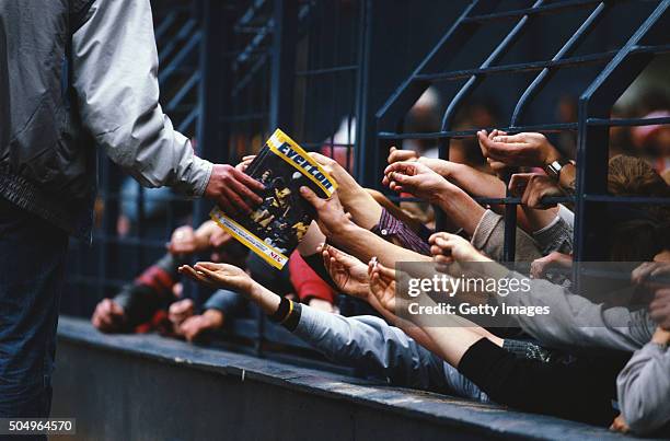 Programme seller sells match day programmes through the safety fences during the First Division match between Everton and Manchester United at...