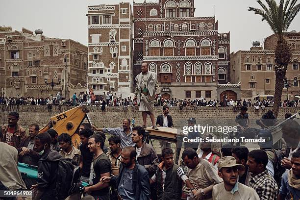 In the historical old city of Sana'a civilians watch as local response teams and Houthi fighters clear the rubble of four houses that were destroyed...