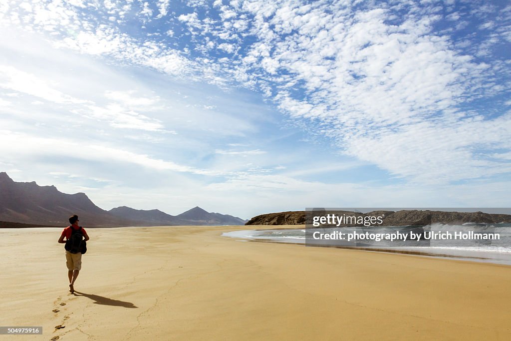 Hiker walking alone at beach, Fuerteventura, Spain