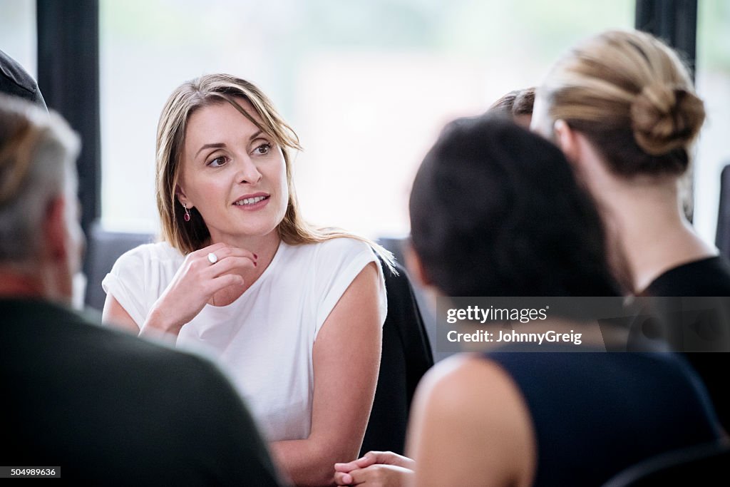 Businesswoman with hand on chin listening to colleague in meeting