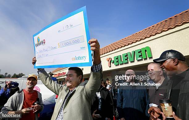 Chino Hills 7-Eleven franchise owner Balbir Atwal, of Yorba Linda, and originally from Punjab, India, holds his $1 million check Powerball during a...