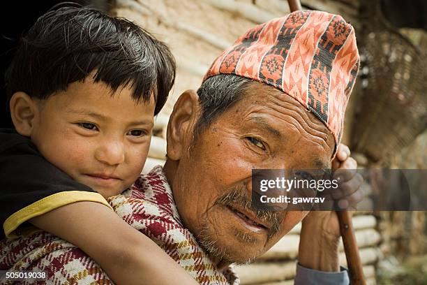 outdoor rural image of grandchild on grandfathers piggyback. - nepal man stock pictures, royalty-free photos & images