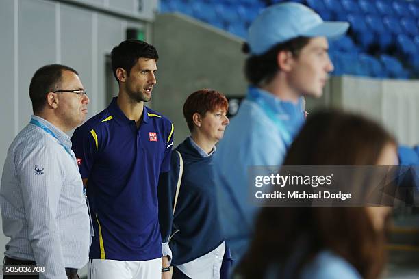Novak Djokovic of Serbia keeps an eye on Kei Nishikori of Japan from the stands during a practice session ahead of the 2016 Australian Open at...