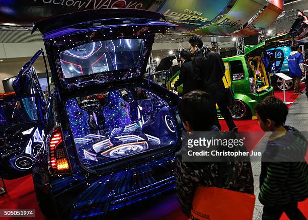 Two boys look at the custom audio system inside the interior of a car shown on display at the 2016 Tokyo Auto Salon car show on January 15, 2016 in...