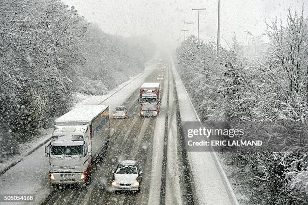 Picture taken on January 15, 2016 shows cars and trucks under heavy snowfall on the E40 highway in Helecine, after a snow front reached the country...