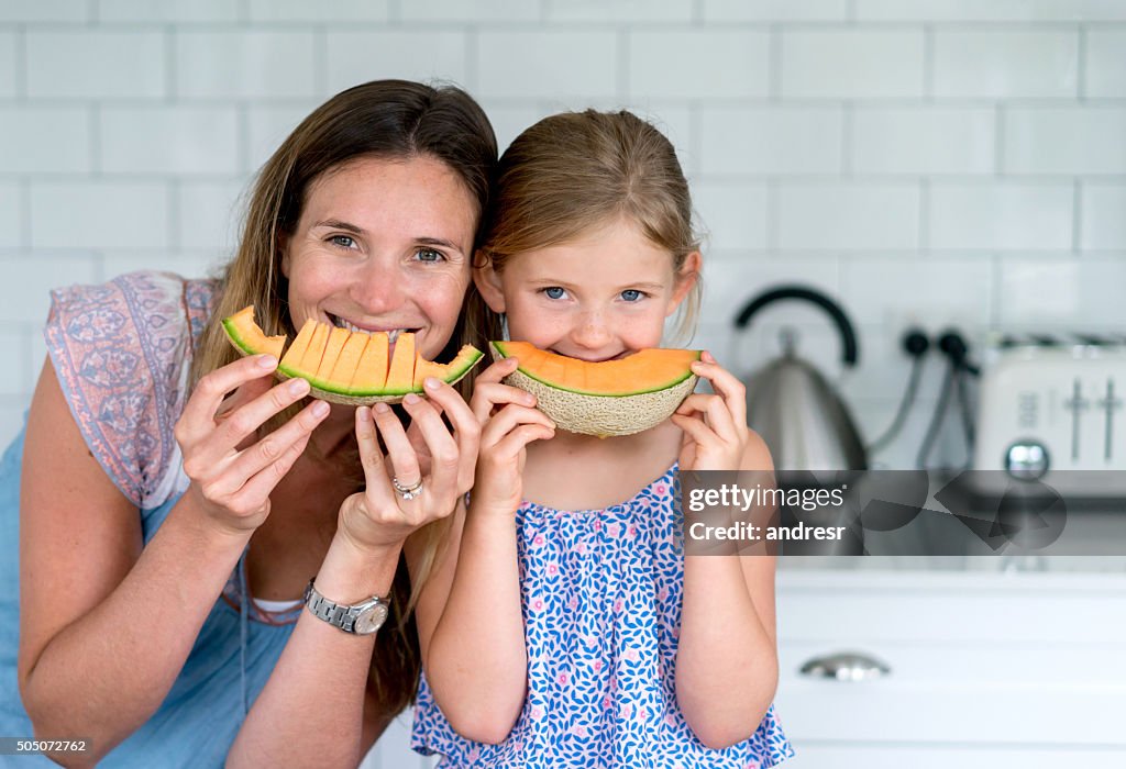 Mother and daughter eating melon