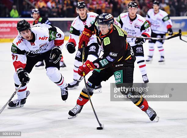 Drayson Bowman of Duesseldorfer EG takes a shot under the pressure of Pascal Zerressen of Koelner Haie during the Ice Hockey DEL match between...