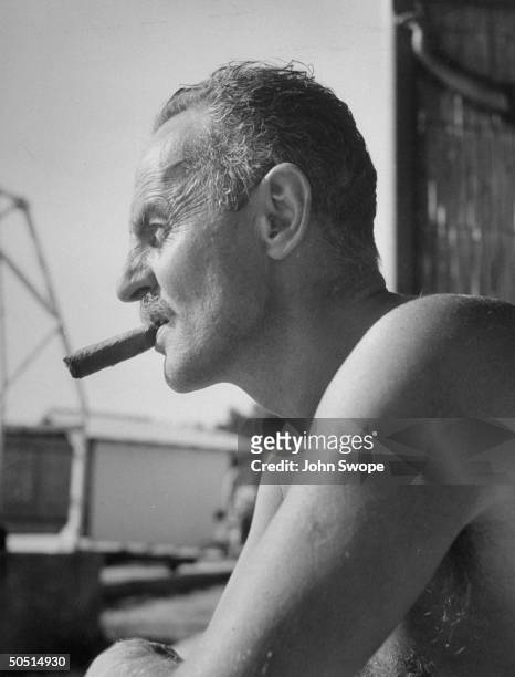 Film producer Darryl F. Zanuck, bare-chested, smoking cigar during visit to Eden Roc.