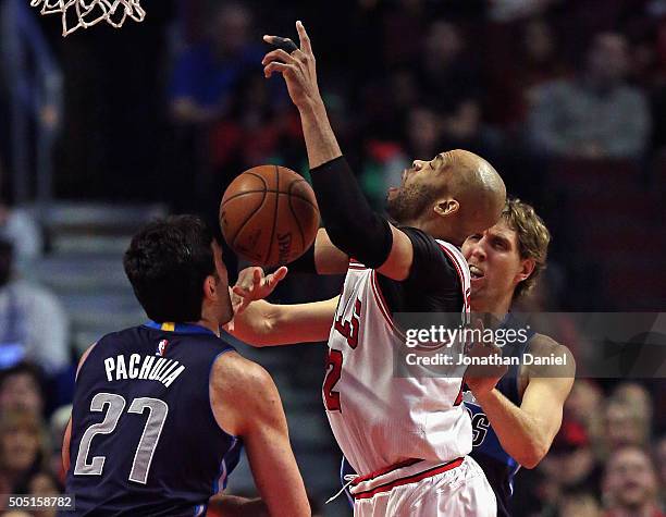 Taj Gibson of the Chicago Bulls is fouled by Dirk Nowitzki of the Dallas Mavericks as he tries to get off a shot against Zaza Pachulia at the United...