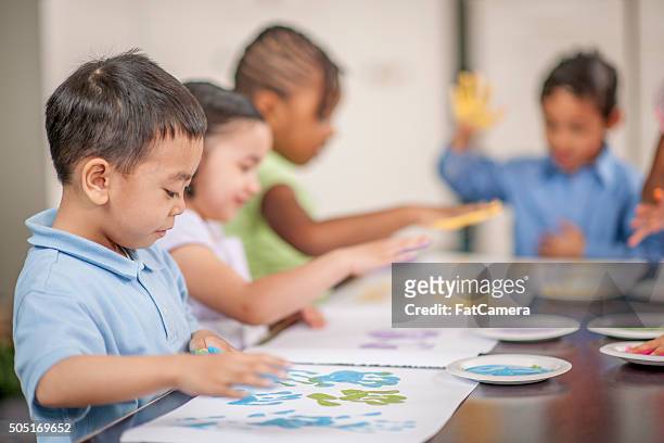 children finger painting for an art project - kids arts and crafts stock pictures, royalty-free photos & images