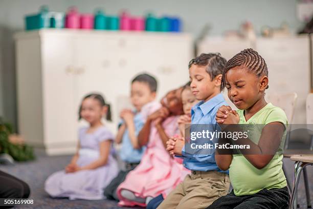 rezar juntos en clase - niños orando fotografías e imágenes de stock