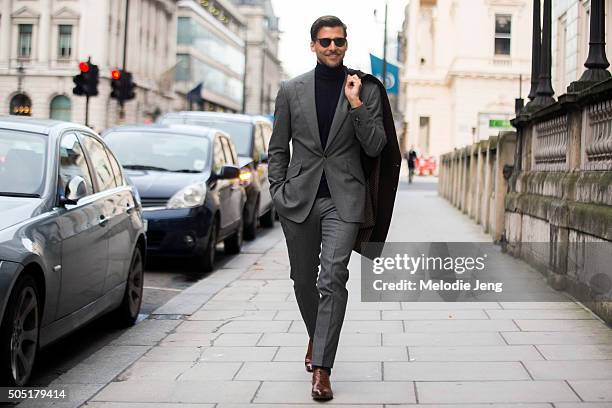 Model Johannes Huebl attends the Pringle of Scotland show in a gray Marc Anthony tailoring suit and coat, black Brunello Cucinelli turtleneck, and...