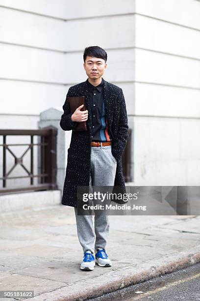 Showgower wears a black and white spot fitted peacoat, gray trousers, and a leather clutch during The London Collections Men AW16 at Victoria House...