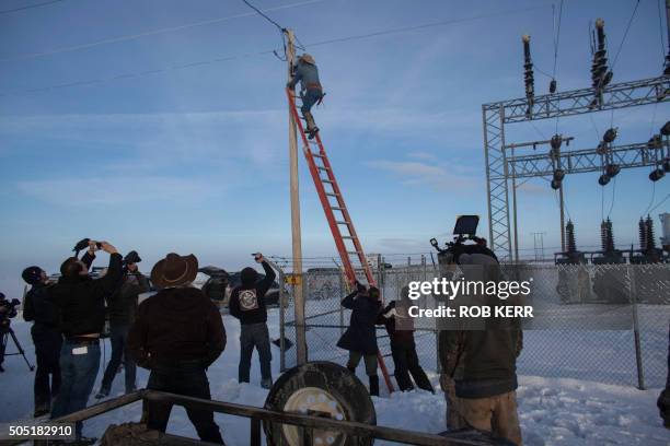 January 15, 2016 in Burns, Oregon. LaVoy Finicum climbs a ladder to disable a power pole remote camera location near the occupied Malheur National...