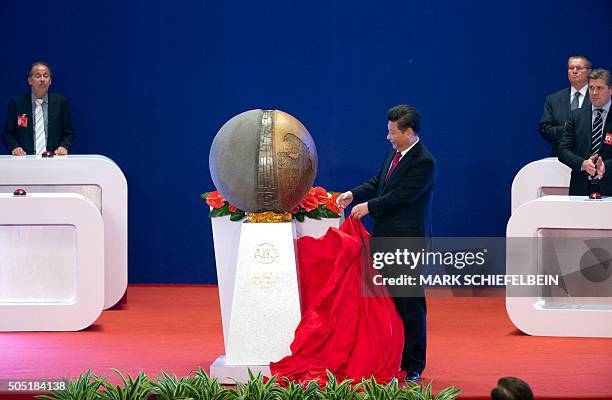 Chinese President Xi Jinping unveils a sculpture during the opening ceremony of the Asian Infrastructure Investment Bank in Beijing on January 16,...