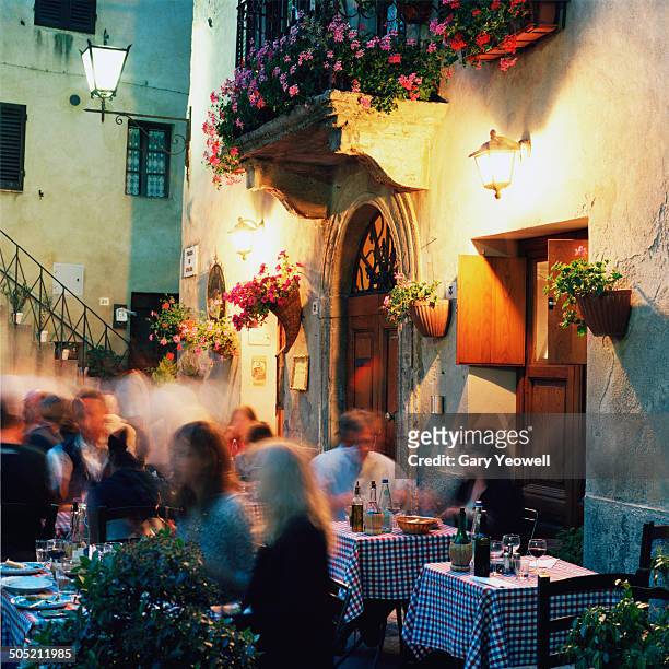 people dining outside a restaurant at night - italien stock-fotos und bilder