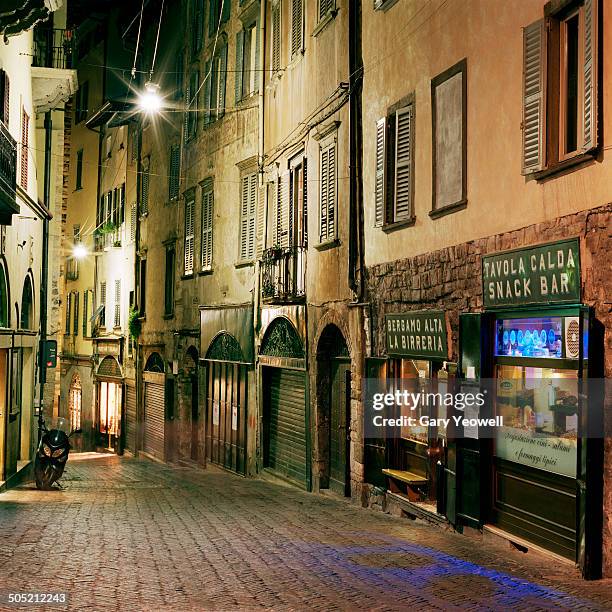 narrow cobbled street in bergamo at night - motorbike shop stock pictures, royalty-free photos & images