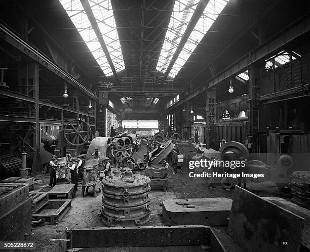 Cammell Laird's Cyclops Ordnance Steel Tyre and Spring Works, Grimesthorpe, Sheffield, Yorkshire, 1913. Men at work in the fettling shop, with huge...