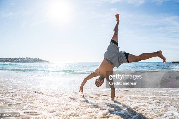 handsome man doing a cartwheel at the beach - cartwheel stock pictures, royalty-free photos & images
