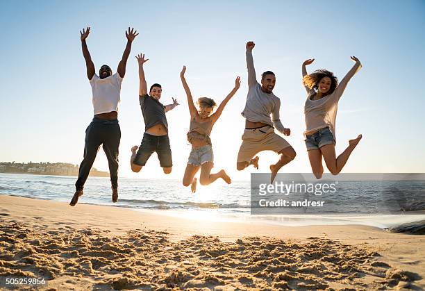 gruppo di amici che saltano in spiaggia - jumping foto e immagini stock