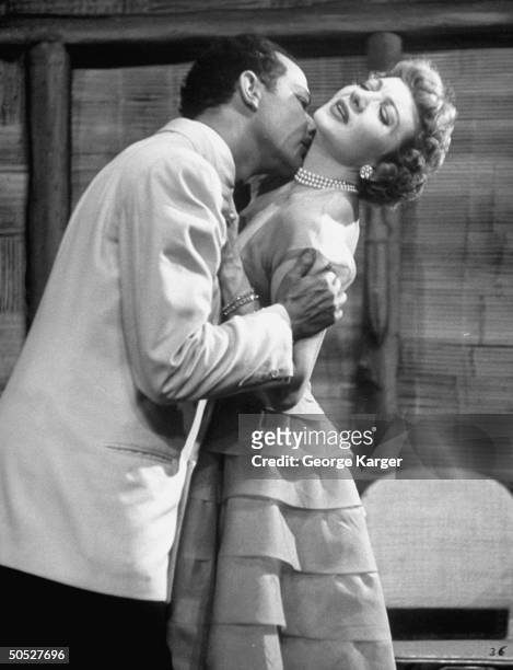 Actress Claudette Colbert, being kissed by Leon Janney in the first straw-hat-circuit appearance of her career, scene from Noel Coward's Island Fling.