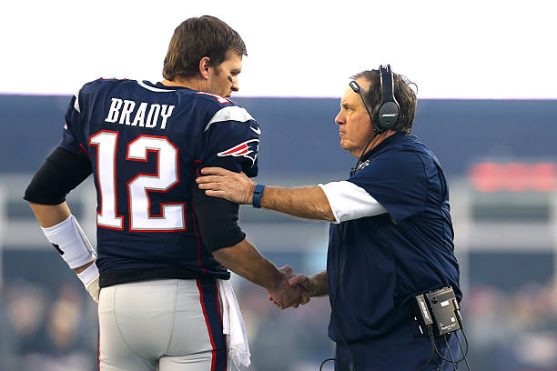 Tom Brady and head coach Bill Belichick of the New England Patriots shake hands at the start of the AFC Divisional Playoff Game against the Kansas...