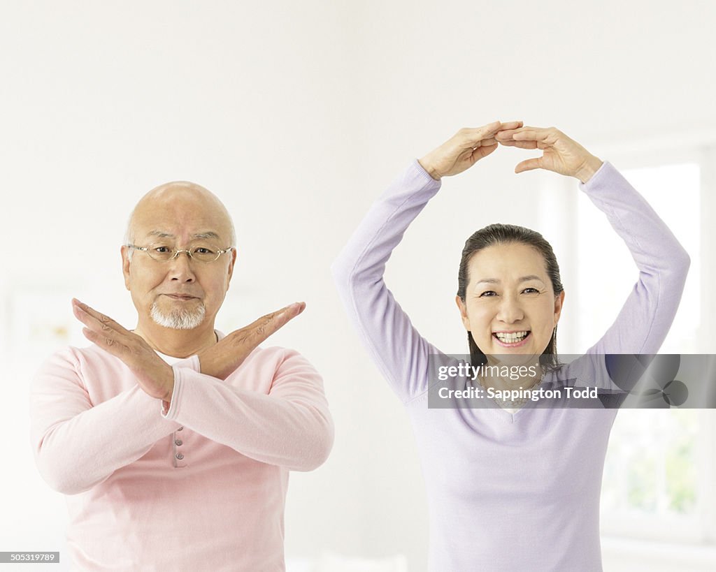 Senior Couple Gesturing Cross And Circle Sign
