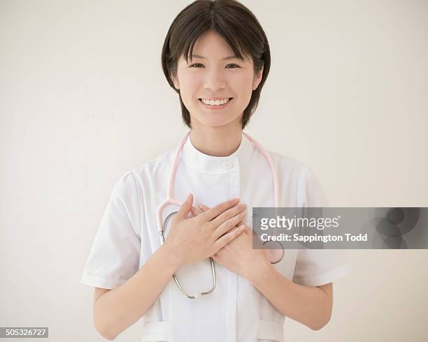 smiling nurse with stethoscope - hands on chest stock pictures, royalty-free photos & images