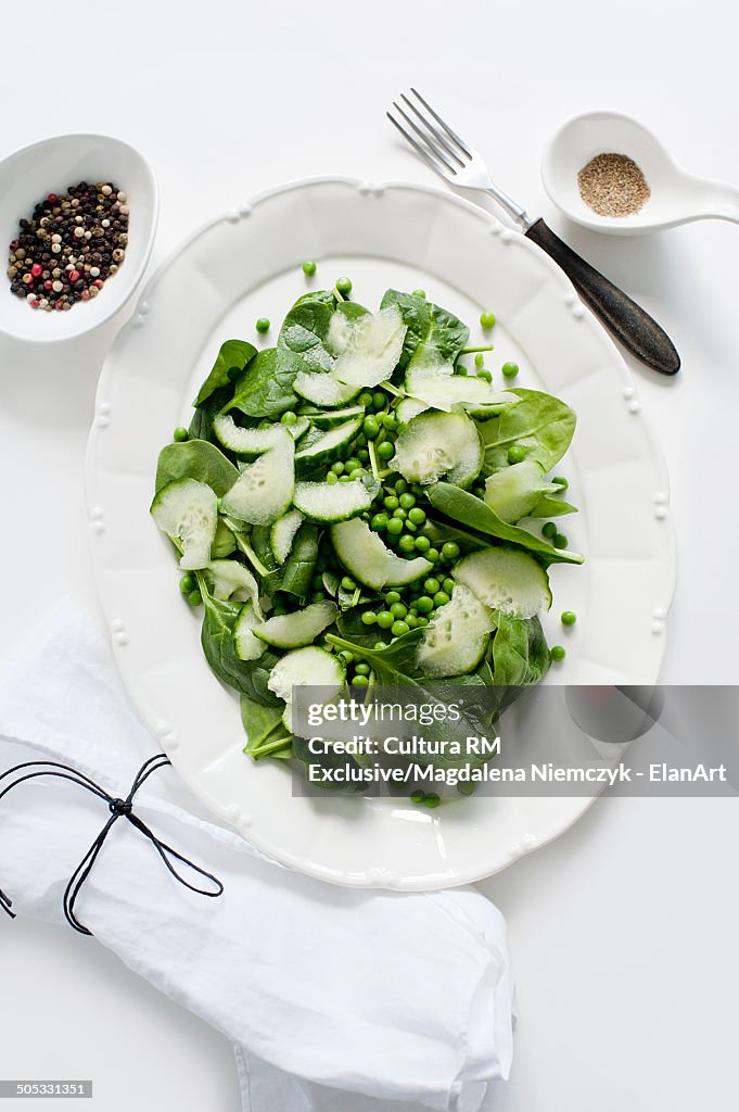 Plate of peas, cucumber and spinach leaf salad