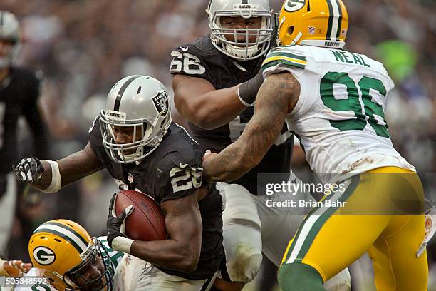 Running back Latavius Murray of the Oakland Raiders slips into the crack for a yard as guard Gabe Jackson keeps linebacker Mike Neal of the Green Bay...