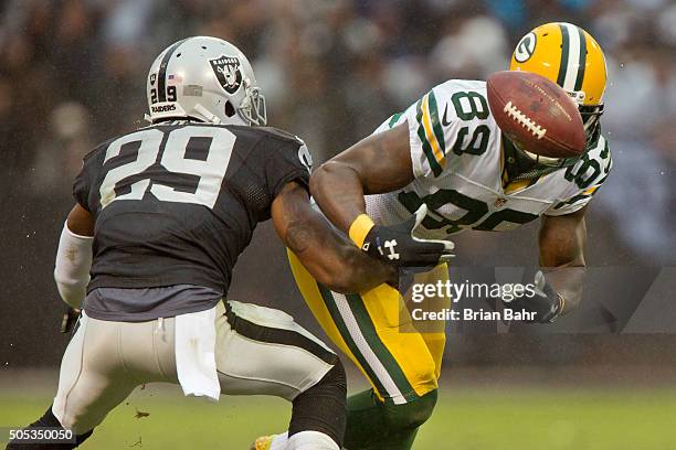 Wide receiver James Jones of the Green Bay Packers bobbles and catches an eight yard pass against cornerback David Amerson of the Oakland Raiders to...