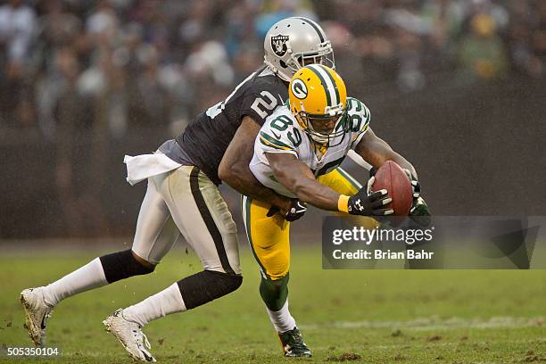 Wide receiver James Jones of the Green Bay Packers bobbles and catches an eight yard pass against cornerback David Amerson of the Oakland Raiders to...