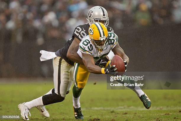 Wide receiver James Jones of the Green Bay Packers bobbles and catches an eight yard pass against cornerback David Amerson of the Oakland Raiders to...