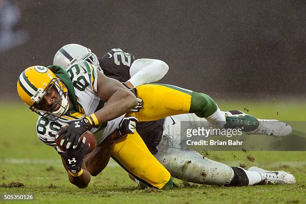 Wide receiver James Jones of the Green Bay Packers bobbles and catches an eight yard pass against cornerback David Amerson of the Oakland Raiders to...