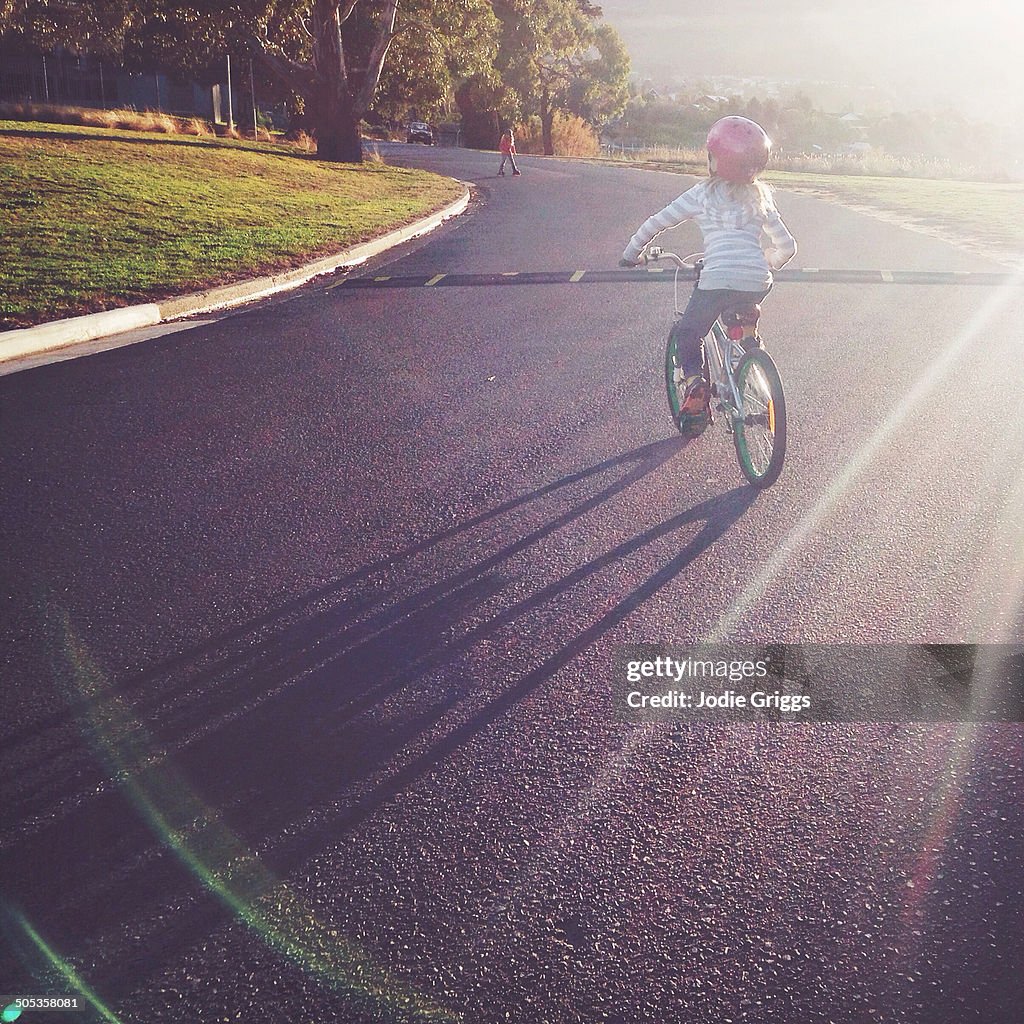 Child riding bike outside in late afternoon sun