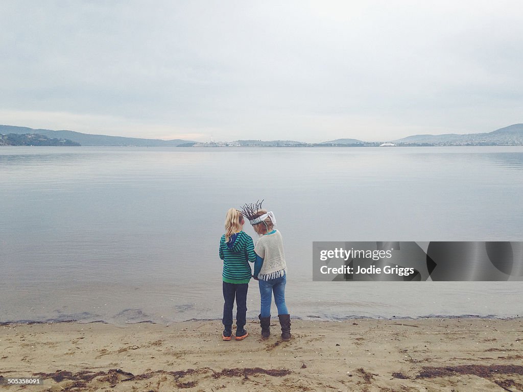 Two children standing together beside a river