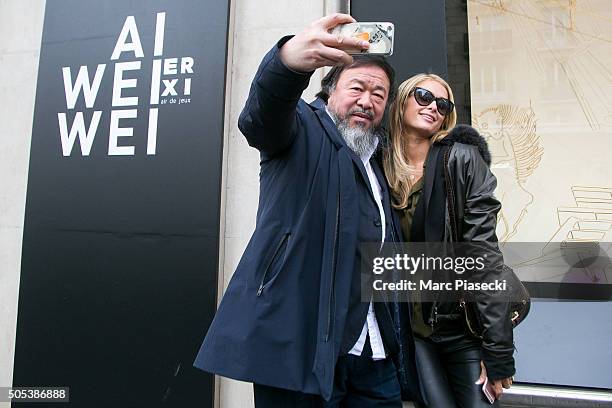 Paris Hilton poses for a selfie with artist Ai Wei Wei as they visit the 'Ai Wei Wei Er Xi' exhibition at Le Bon Marche department store on January...