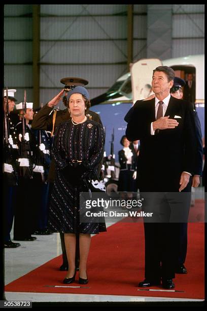 President Ronald Reagan proudly holding hand over heart during American National Anthem as he stands beside England's Queen Elizabeth II during her...