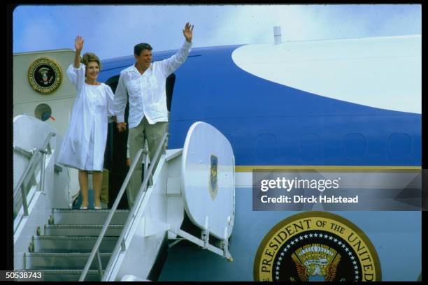 President Ronald Reagan and wife Nancy waving from outside the doorway of Air Force One.